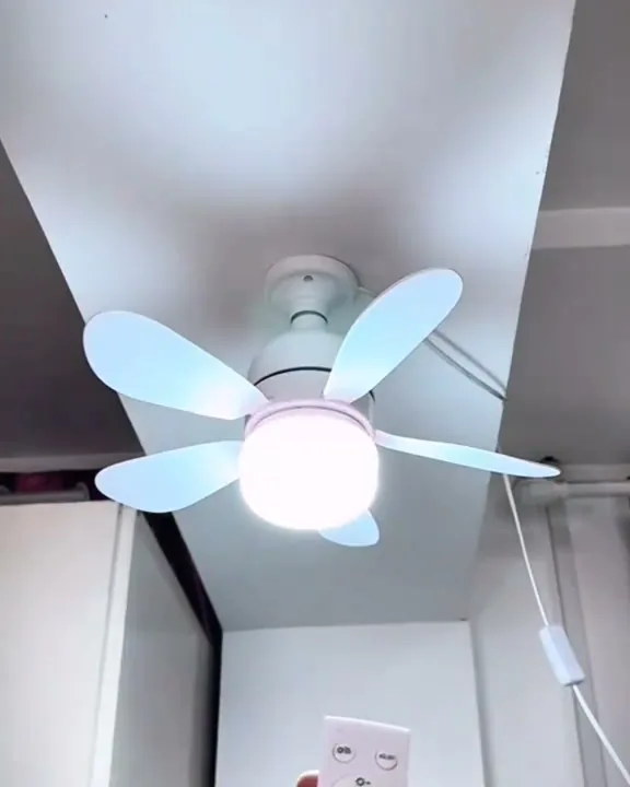 Ventilador aceso no teto e controle remoto na mão