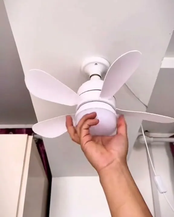 Mão rosqueando o ventilador LED no bocal do teto